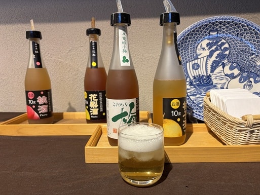 数種類の果実酒の瓶とコップに入れた果実酒