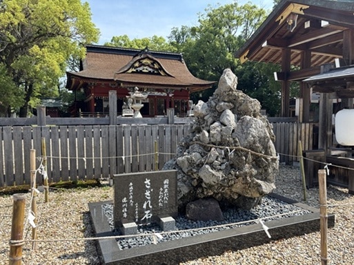石や岩がかたまってできたさざれ石とその奥にある拝殿